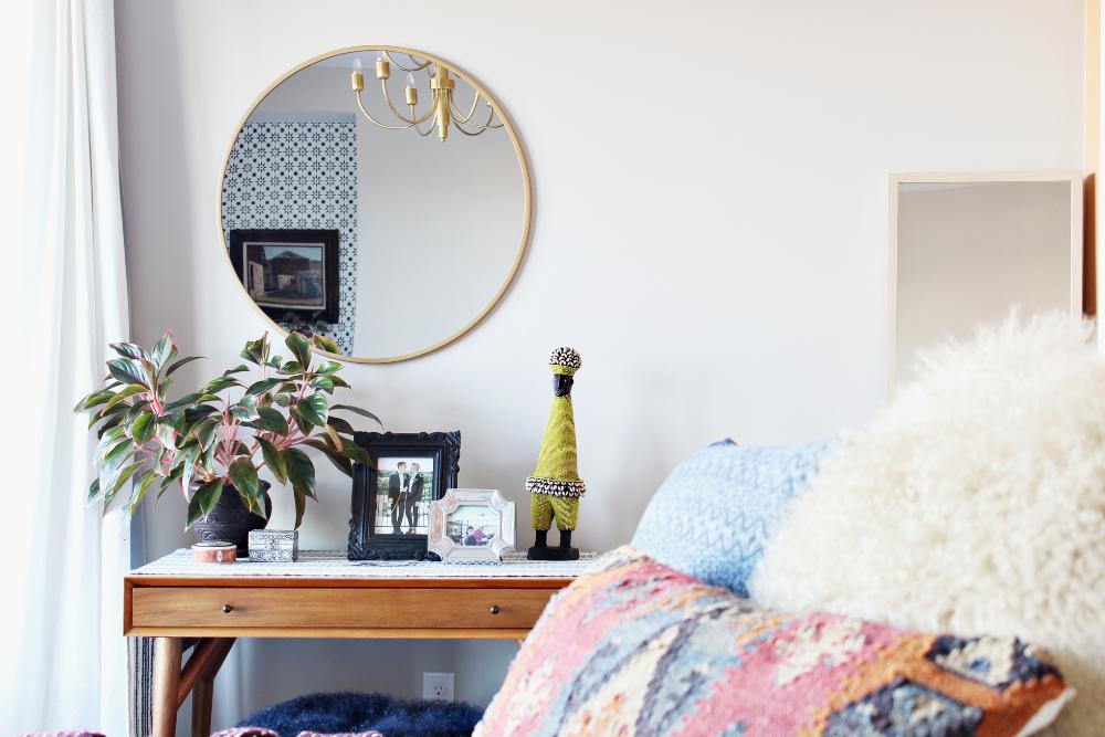A circular gold mirror over a wood desk